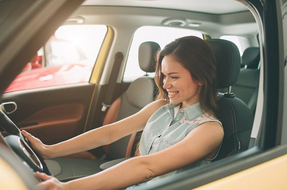 Closeup portrait happy, smiling, young attractive woman, buyer sitting in her new car isolated outside dealer, dealership lot office. Personal transportation, auto purchase concept
